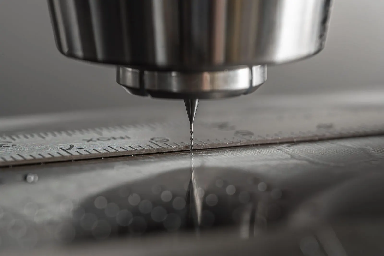 Close-up of a CNC milling machine drill bit positioned above a metal workpiece
